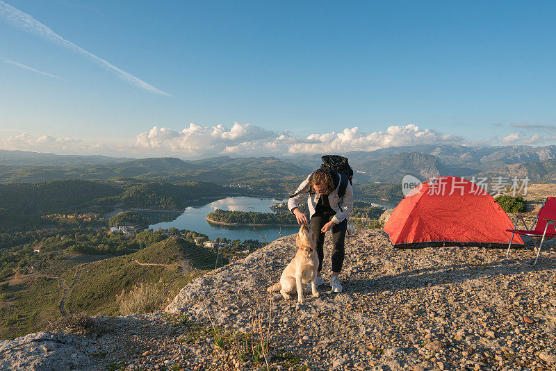 一个年轻人和她的狗在山顶露营