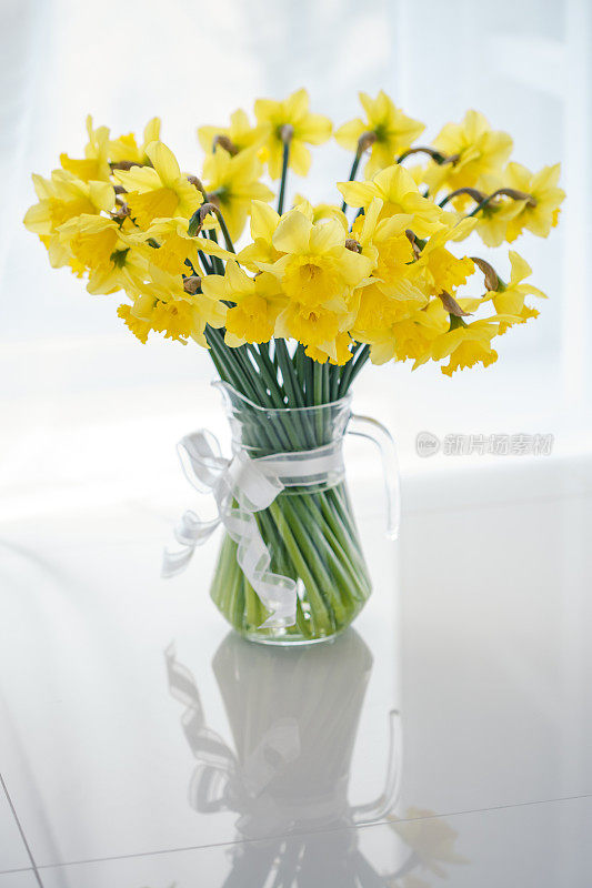 玻璃花瓶里盛开着大量的黄色水仙花