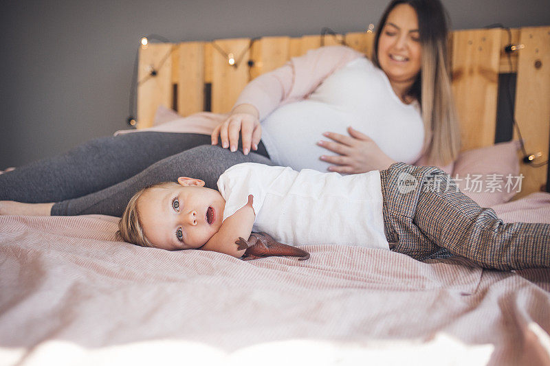 怀孕的妈妈和年幼的儿子在卧室里玩耍