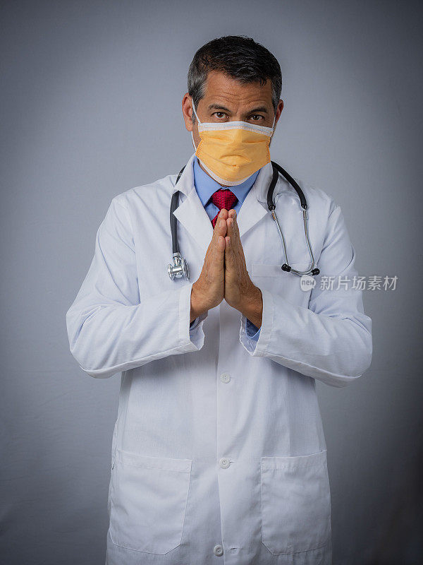 一幅医生戴着外科口罩望着摄像机祈祷的肖像