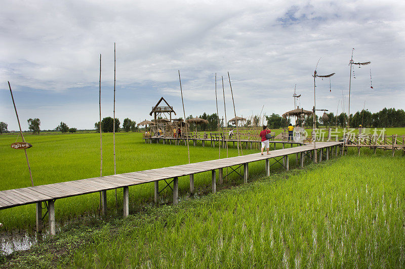 泰国人和外国游客在稻田里的木桥上旅游参观