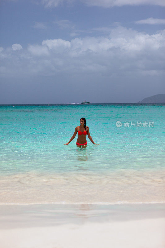 在加勒比海的热带海滩上，一个女人从水里出来