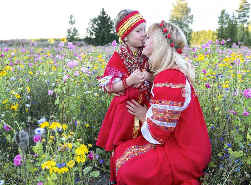 家人，女孩和5岁的孩子穿着红白相间的裙子。白俄罗斯，乌克兰，俄罗斯的民族服装。妈妈拥抱和亲吻她的女儿。