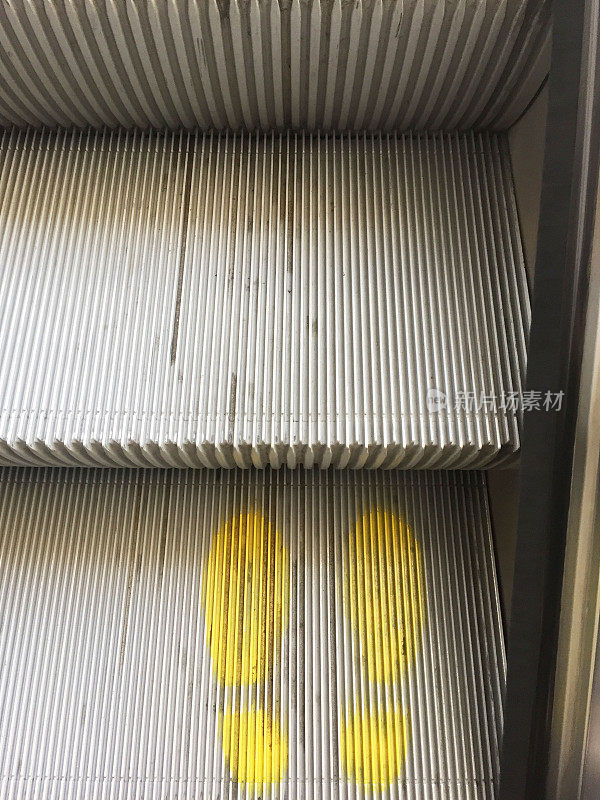 社交距离:在自动扶梯的台阶上，黄色脚印表示社交距离