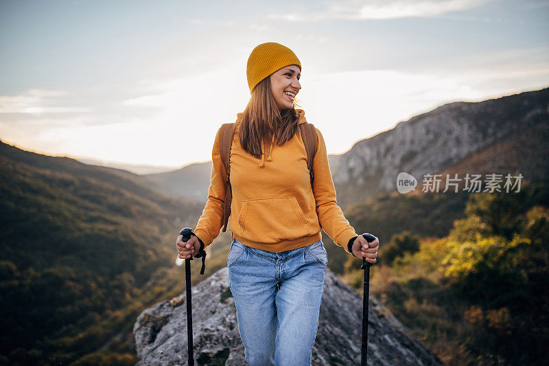 在秋天的一天，年轻女子背着背包在山里徒步旅行
