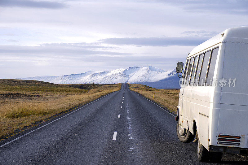 一辆白色巴士停在冰岛的沙漠山路上