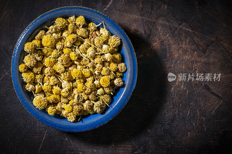 洋甘菊干花茶在黑暗的木材背景