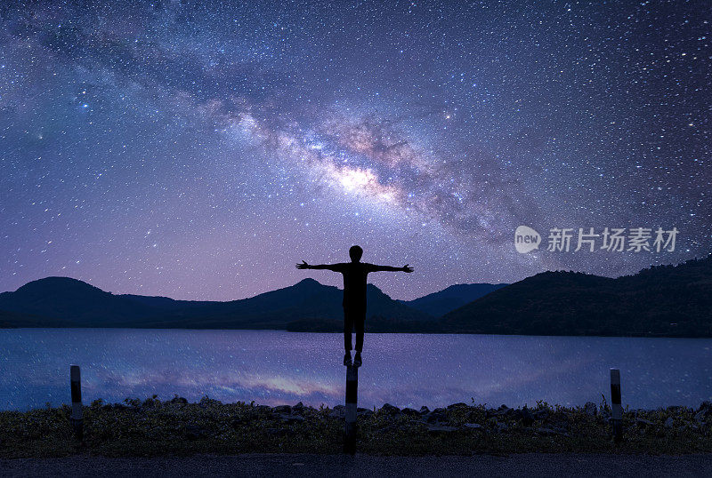 放松男人的剪影站在美丽的夜空与星星和银河。景观银河系