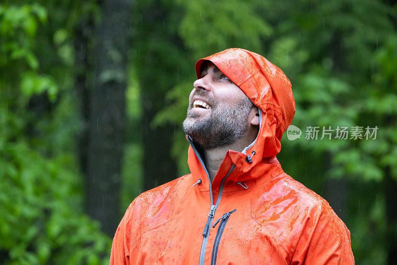 雨中漫步森林，穿着雨衣的快乐男人