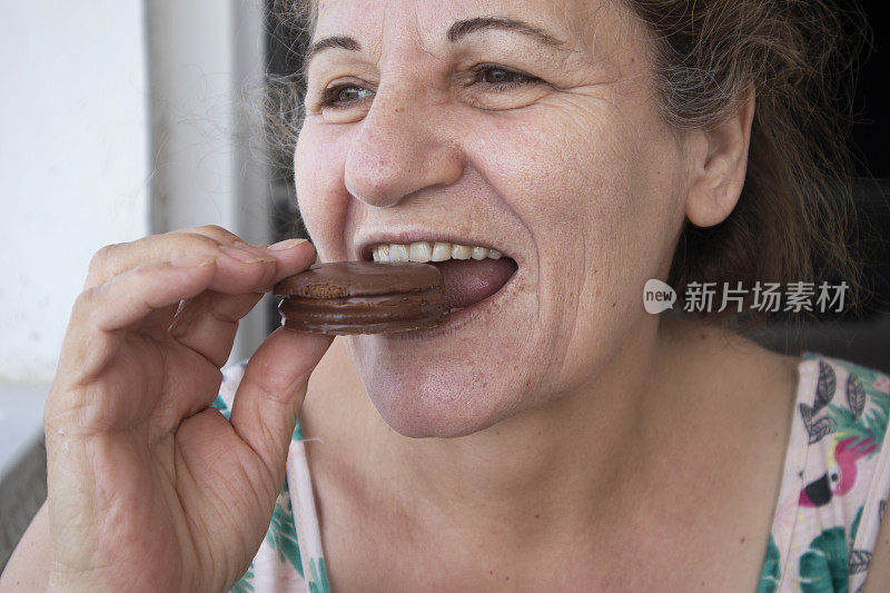 快乐的老年妇女在吃巧克力饼干