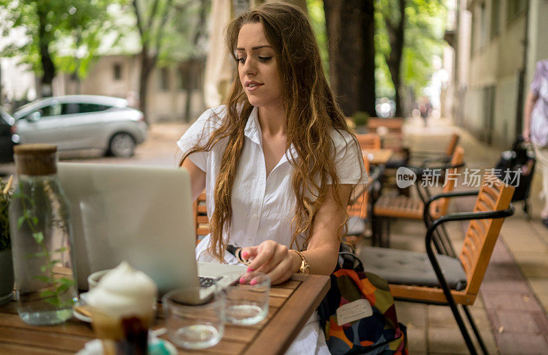 女商人一边用笔记本电脑一边在咖啡桌上喝着咖啡享受工作