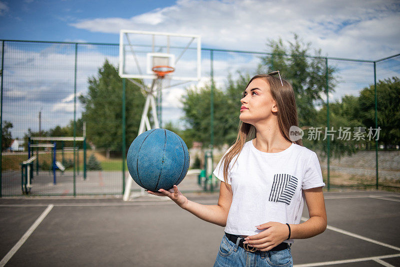 一个漂亮的年轻女子在篮球场上