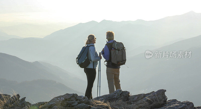 成熟的徒步旅行夫妇在日出时在山脊上放松