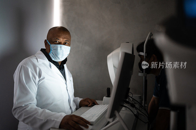 一名验光师戴着防护口罩在诊所检查病人的肖像