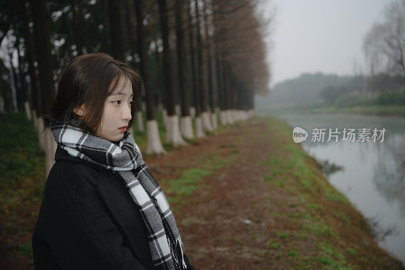 亚洲女孩走在河边的雨天