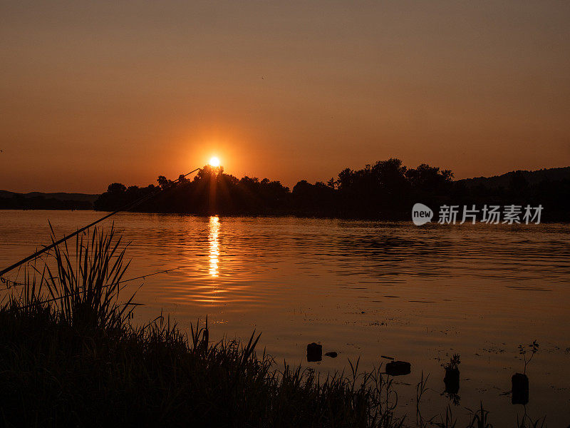 黄金时段日出日落，有人在河边钓鱼