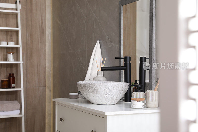 浴室的白色台面上有石制水槽和水龙头和洗漱用品