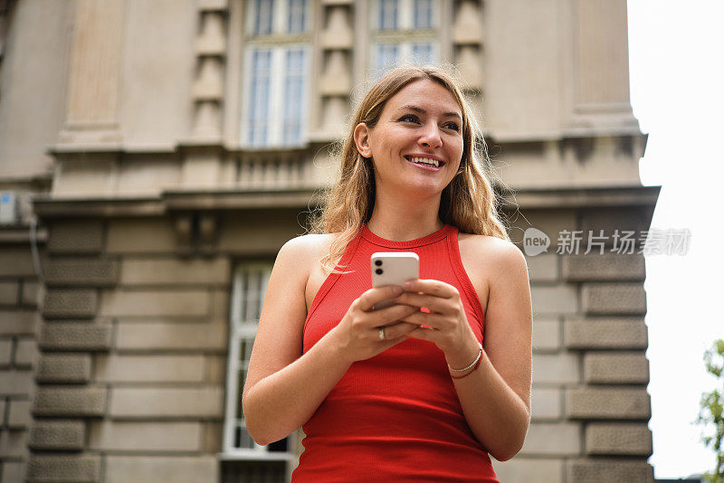 一个美丽的年轻女子在城市中使用智能手机的肖像