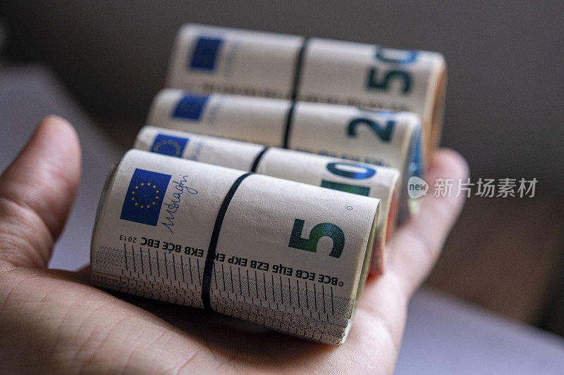 手里拿着许多用橡胶包着的欧元。