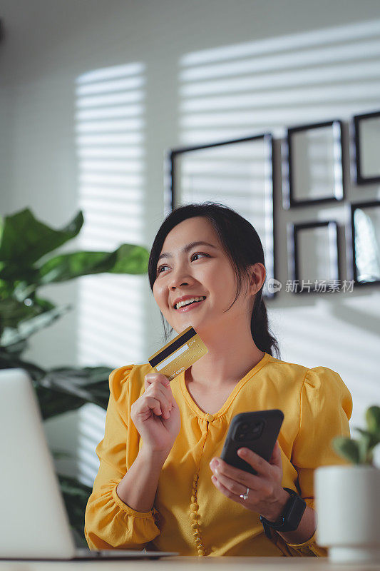 亚洲女性喜欢网上购物，持有信用卡，在家办公时使用智能手机在线支付。