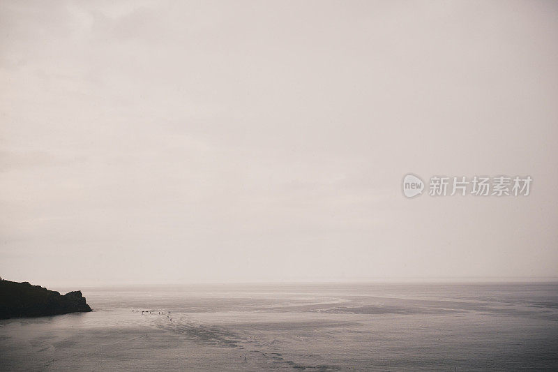 康沃尔的纽基湾，阴云密布，阴云密布，阴云密布。远处有一群认不出来的划桨者。