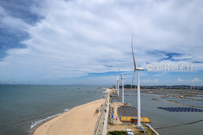 在海边阳光明媚的海滩上，风力涡轮机的鸟瞰图