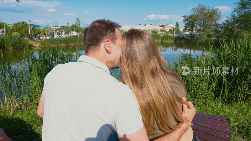 在公园湖边的长凳上，男人拥抱了女人