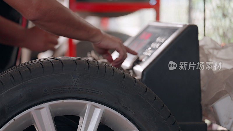 汽车修理工有修理汽车的专业知识和技能，他们在车库里给合金轮毂装上新轮胎后，用专门的机器测试车轮的转速。车轮平衡。轮胎配件。汽车维修及服务。综合汽车维修中心