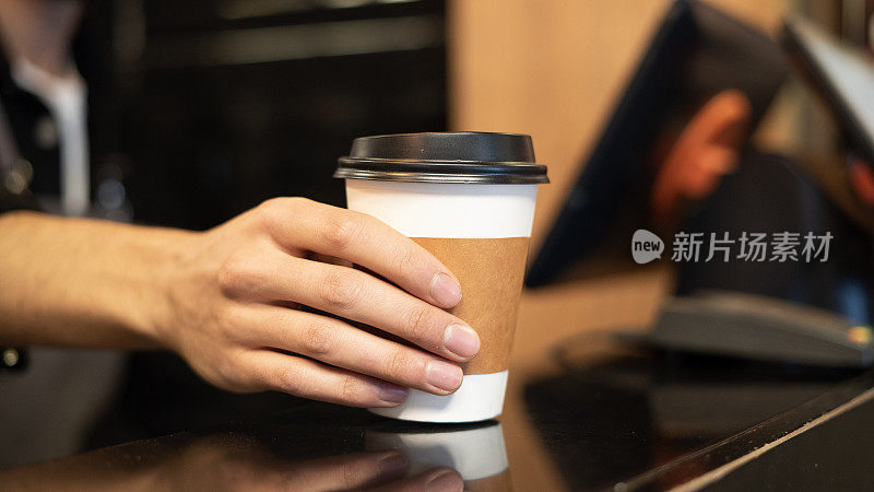 特写:咖啡师把硬纸板杯子放在柜台上