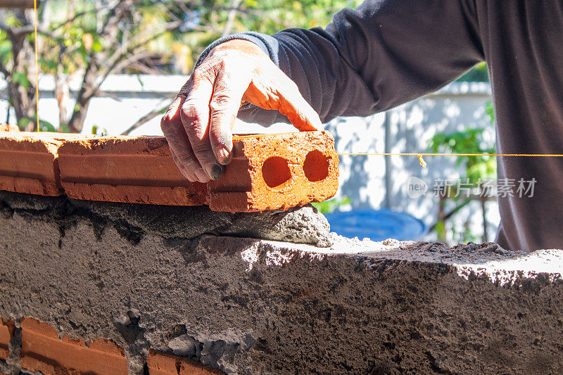 在建筑房屋施工中，抹灰后工人的手在砌砖