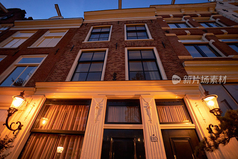 阿姆斯特丹历史悠久的运河房屋建筑立面与夜晚的街灯