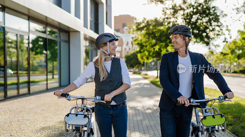 夫妻在城市中穿梭，在街上骑着自行车聊天和散步。在漫长的工作日后骑自行车下班的中年城市上班族。