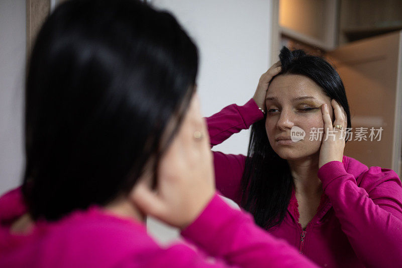 伤心的女人看着自己眼睛上的淤青