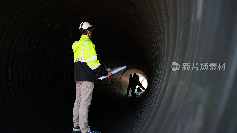 工程师手拿图纸底图规划了一条地下大管道的污水隧道