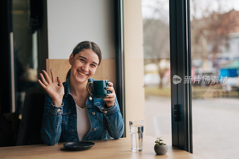 一个年轻漂亮的女孩坐在咖啡厅里，手里拿着一杯热饮。