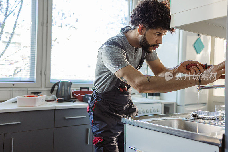 西班牙裔水管工正在修理客户家厨房水槽的漏洞