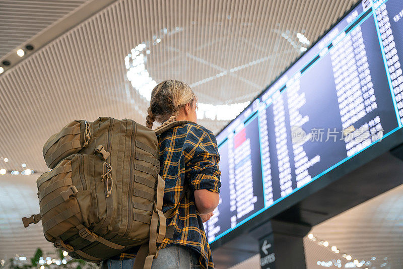 背着背包的女子在机场检查登机时间。在抵离登机板前等候