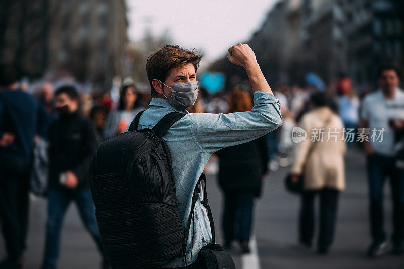 一名男性抗议者举起拳头的后视图