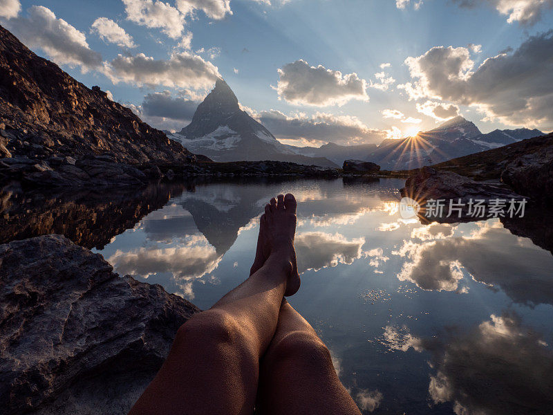 一个女人光着脚坐在湖边的岩石上，远处的马特洪湖