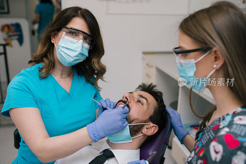 牙医和她的助手治疗年轻人的牙齿。