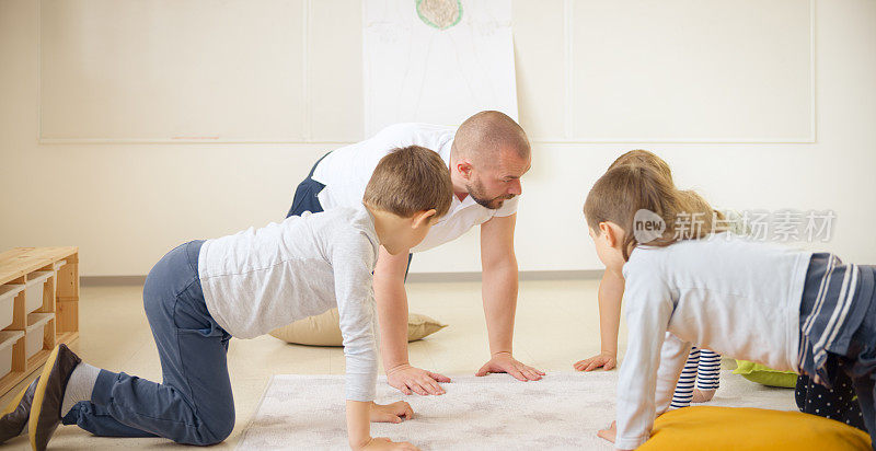 老师和他的学生四肢着地，在教室地板上学习身体动作