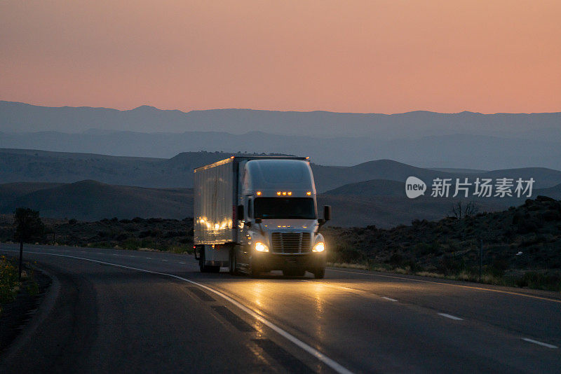 一辆商业货运半挂车向东驶去交付，一个戏剧性的日落背景