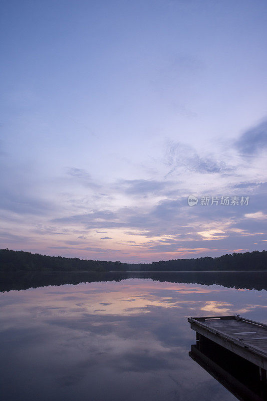 黎明前的云朵笼罩着宁静的湖面和质朴的码头