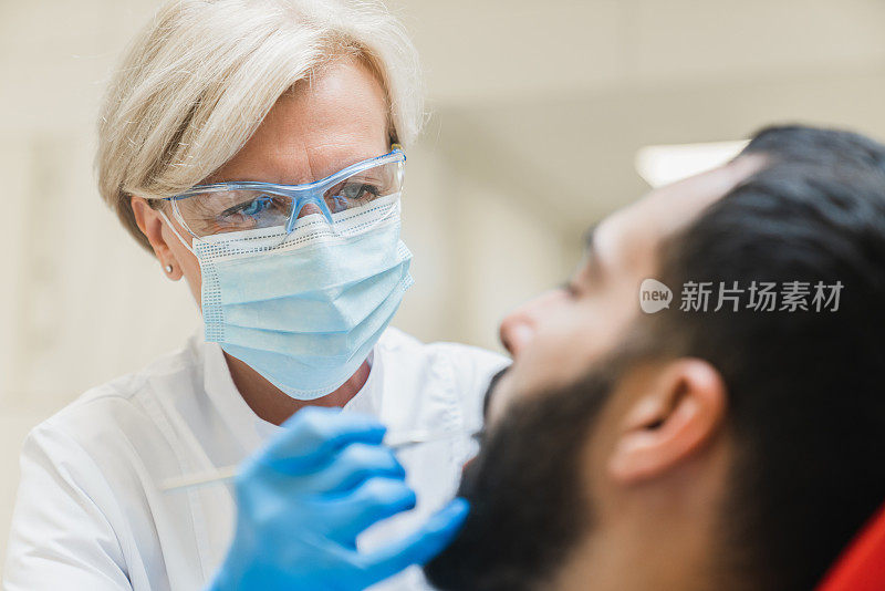 口腔手术的特写照片。牙科医生在正畸诊所治疗男性患者口腔内的治疗牙