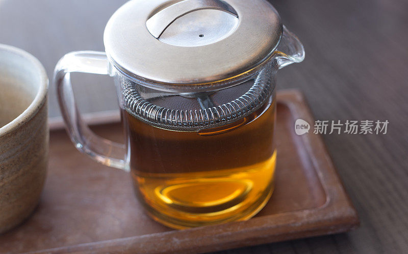 玻璃茶壶中的茶，托盘上的陶瓷杯