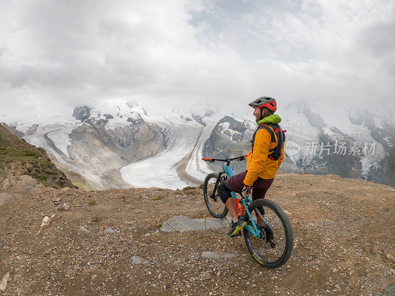 男性山地自行车爱好者欣赏风景，土路，远处的冰川