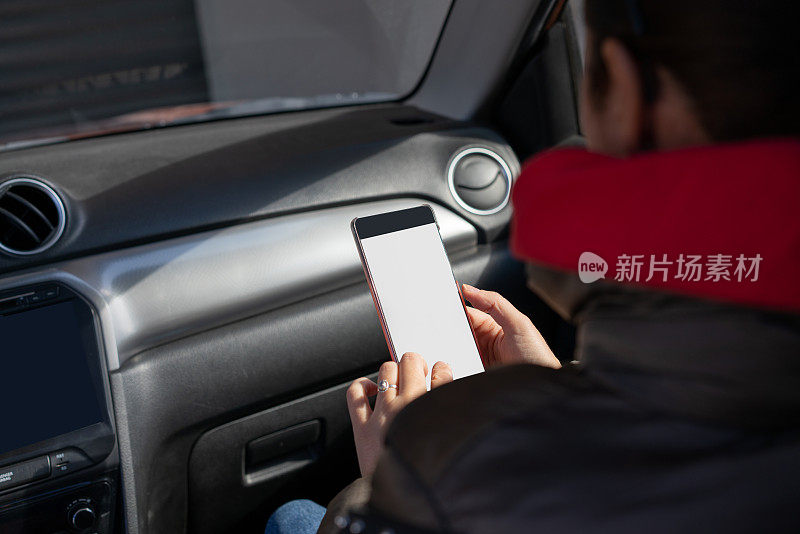 女人在车里手拿智能手机。