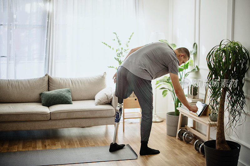一个装着假腿的年轻人在家里练瑜伽