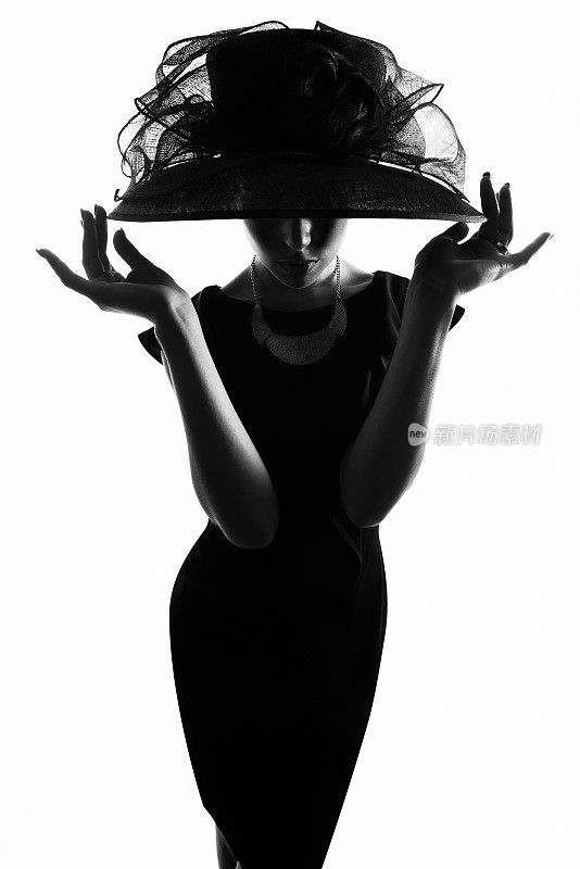 摄影工作室拍摄的一个时尚的女人剪影，在白色的背景下戴着宽边帽子