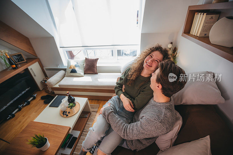 幸福的年轻夫妇在家里放松，在沙发上享受闲暇